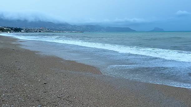 istock Waves gently rolling onto the serene beach, under a beautiful yet cloudy sky above 2213776690