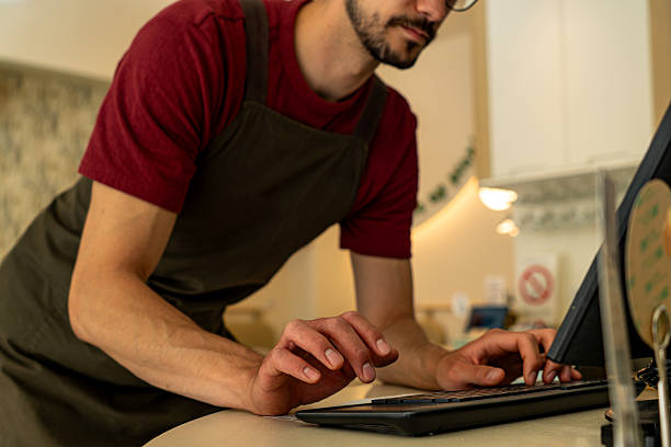 istock Shopkeeper typing on a computer keyboard at the counter 2213778875