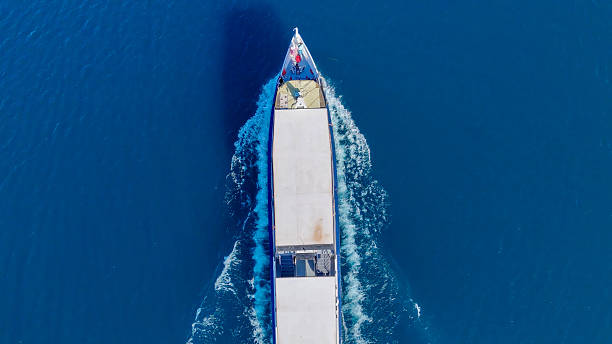 istock Vessel gliding through clear blue waters under a bright midday sun near a serene coastline 2213780059
