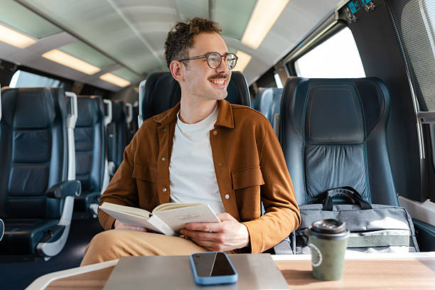 istock Man reading a book on a train journey during daytime 2213782079