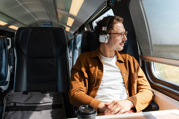 istock Man enjoying music while traveling on a modern train and gazing outside. 2213782142
