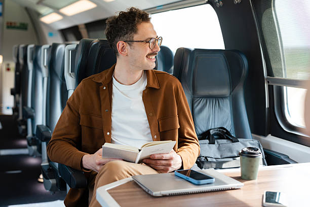 istock Man reading a book while traveling on a train during the day 2213782259