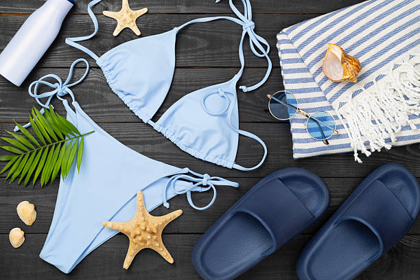istock Blue bikini with beach accessories on wooden background, top view 2213789976