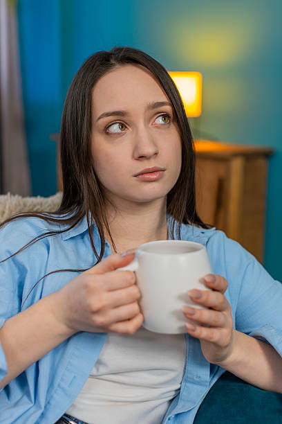 istock Sad young woman sitting on sofa drinking tea feeling lonely thoughtful mood melancholic atmosphere 2213790144