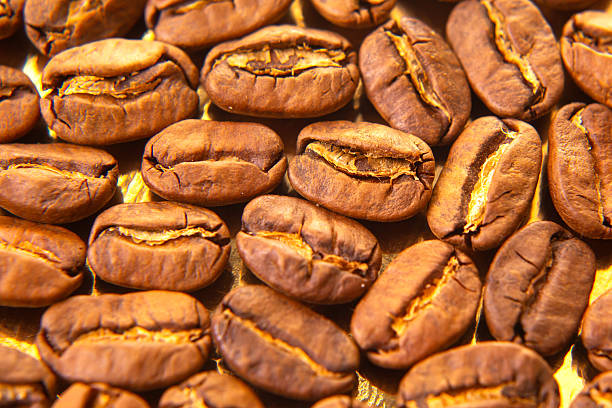 istock Macro shot of aromatic roasted coffee beans on a reflective golden surface, highlighting texture and color for culinary use. 2213790167
