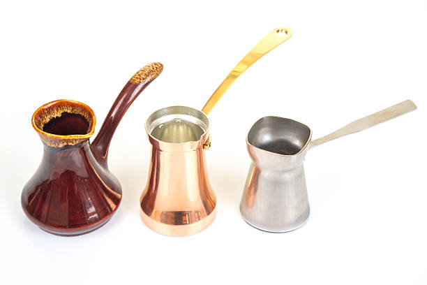 istock Diverse Turkish coffee pots including stainless steel, ornate ceramic, and copper with brass handles, arranged on a white background, suited for traditional coffee brewing and kitchen art shots. 2213790520