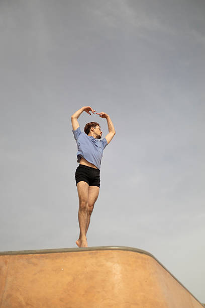 istock Young male dancer performing on rooftop under cloudy sky 2213791592