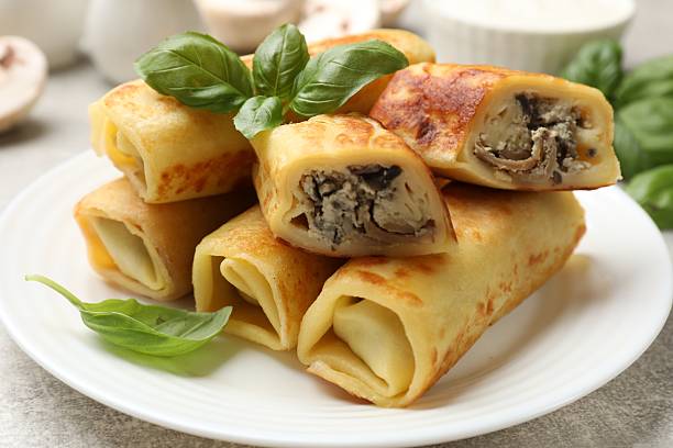 istock Delicious rolled crepes with mushrooms and basil on grey table, closeup 2213794024