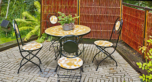 istock Charming outdoor seating area with a mosaic table and chairs surrounded by lush greenery 2213800979