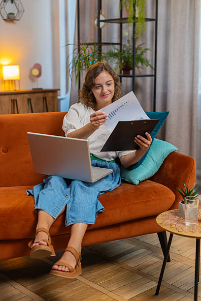 istock Woman accountant using laptop working with financial graph documents, reports of home income on sofa 2213808424