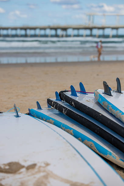 istock Stacked surfboards on beach with ocean and pier in background 2213811342