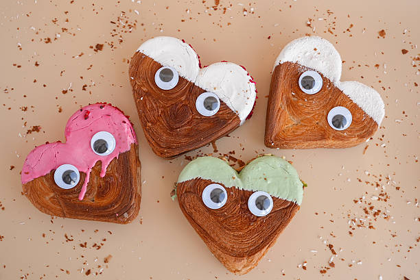 istock Funny eyes creative ides Valentine's Day flat lay top view Holiday celebration Heart shaped different variety flavor croissants on beige background with copy space. Puff pastry new trendy sweet dessert bakery. Creamy dough 2213813701