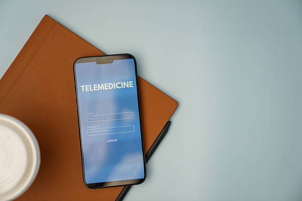 istock Smartphone Displaying Telemedicine Login Screen with Notebook on Desk 2213817898