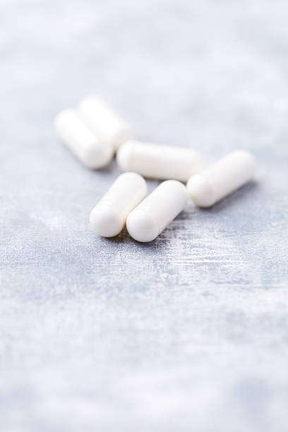 istock Creatine capsules on bright wooden background. Soft focus. Close up. Copy space 2213820139