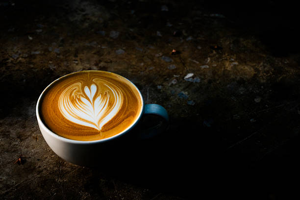 A cup of coffee with latte art on concrete loft background dark mood and tone style. Latte