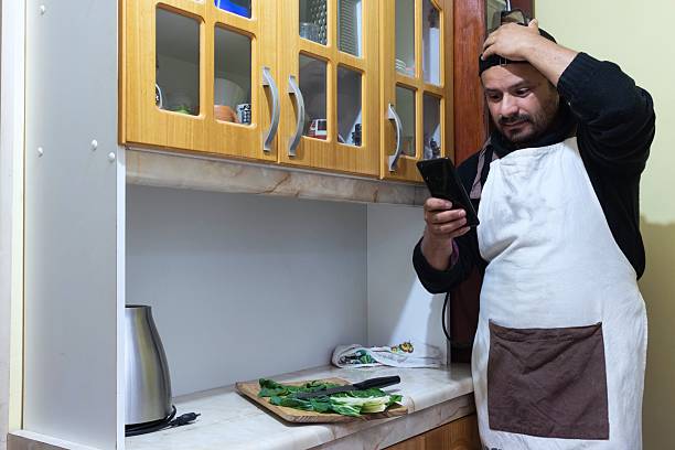 man checks his phone while cooking