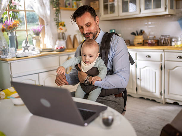 istock Father holding baby while using laptop/working from home 2213827717