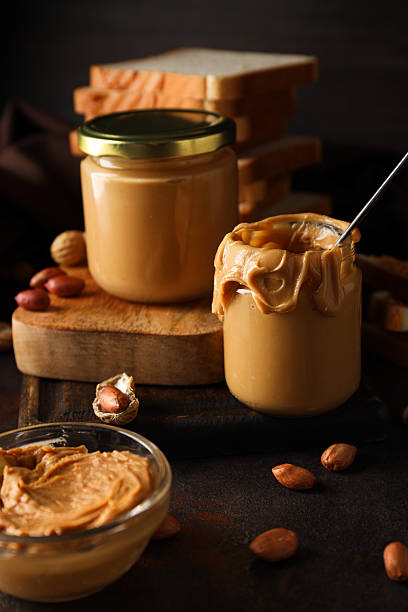 istock Peanut paste in a glass jar, on a dark background. 2213827974