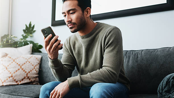 istock Man, phone and relax with texting on sofa, home and check notification for web chat in living room. Person, smartphone and scroll on mobile app, search or contact on social network in lounge at house 2213829300