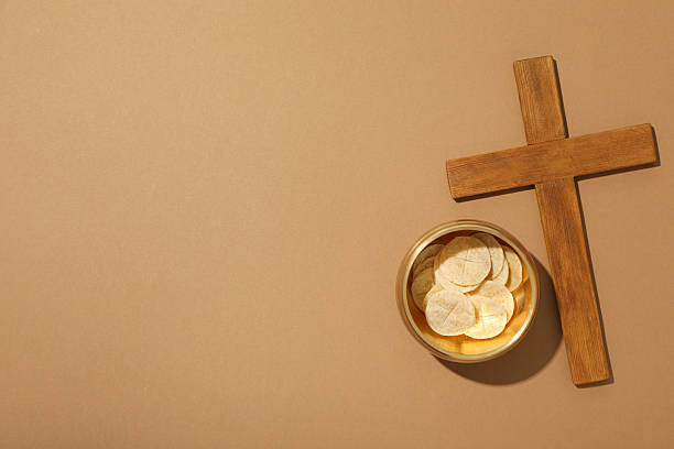 istock Wooden cross and liturgical bread on brown background, space for text 2213829916