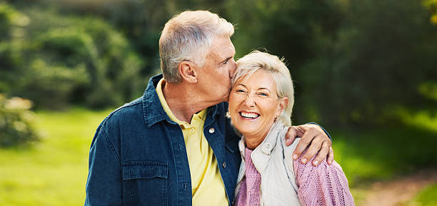 istock Kiss, happy and old couple in park for support, commitment and relax together outdoors in morning. Retirement, nature and senior man and woman laugh embrace for bonding, relationship or romance 2213832095