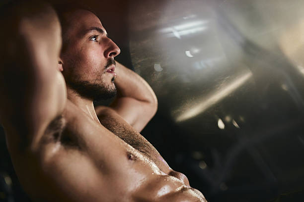 istock Muscular build athlete doing sit-ups in a gym. 2213833471
