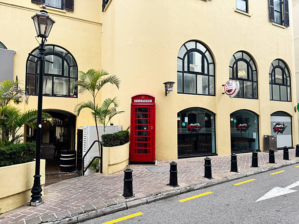Gibraltar, UK - May 01, 2025: A classic British phone box on a charming street in Gibraltar, British Overseas Territory.
