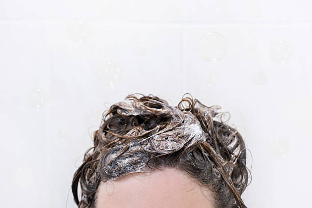 istock A woman washes her hair with shampoo on white background, front view. 2213840157