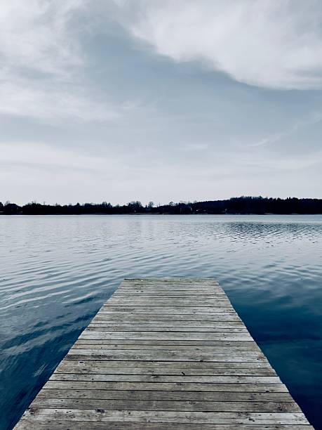 A serene wooden dock extending into a calm lake under a cloudy sky, capturing tranquility and nature's beauty.