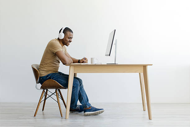 istock Smiling Black Millennial Man In Headphones Studying With Computer At Home 2213841433