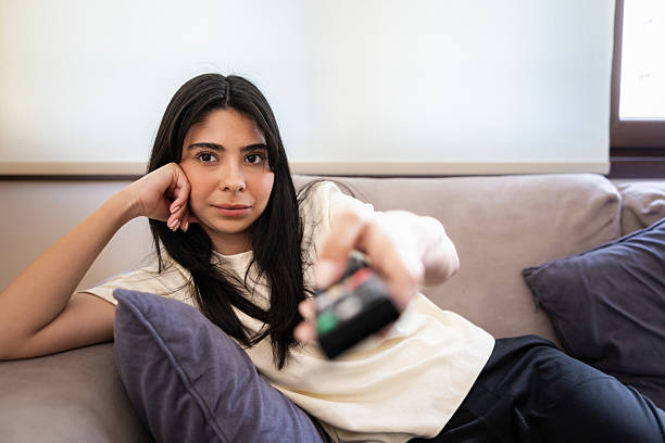 istock Young woman is holding remote control while watching television. 2213841453