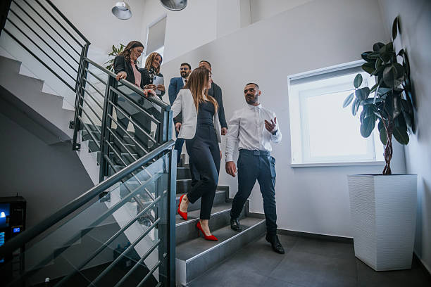 istock Professional colleagues discussing business while descending office stairs 2213845658