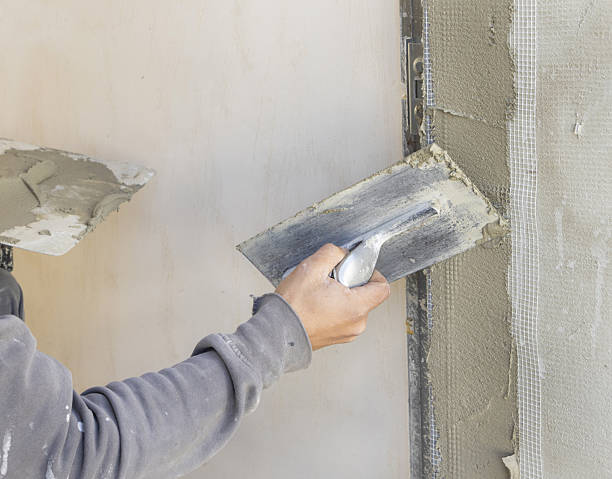 istock Craftsman uses a float trowel and cement to plaster a house wall. Construction process 2213849501