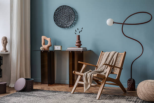 istock A sophisticated space featuring a curved floor lamp, a smoked glass console table, and a rattan chair, enhanced by warm beige walls and organic design elements. 2213850986