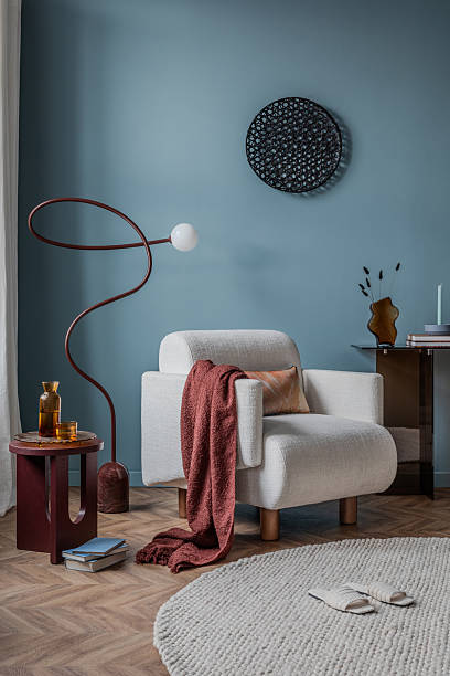 istock Modern sitting area featuring a soft white lounge chair, abstract wall decor, and deep-toned accent furniture. 2213851015