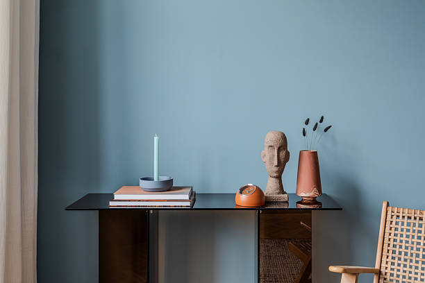 istock Modern console table with pastel candle, abstract head sculpture, and terracotta vase against blue wall. 2213851067