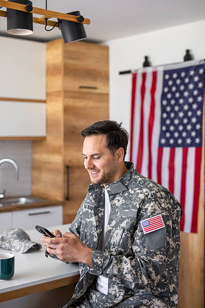 istock Soldier in military uniform drinking coffee and using phone at kitchen table 2213851189