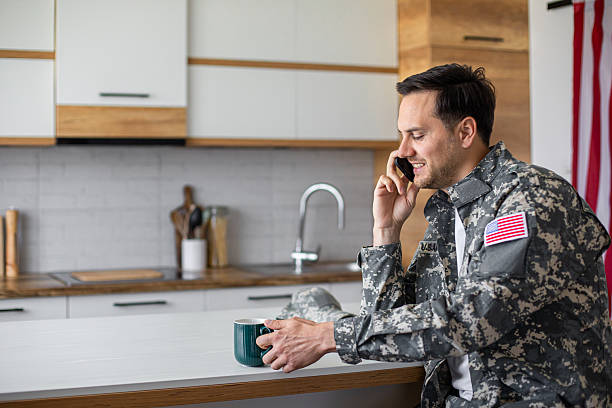 istock Soldier in military uniform drinking coffee and using phone at kitchen table 2213851225