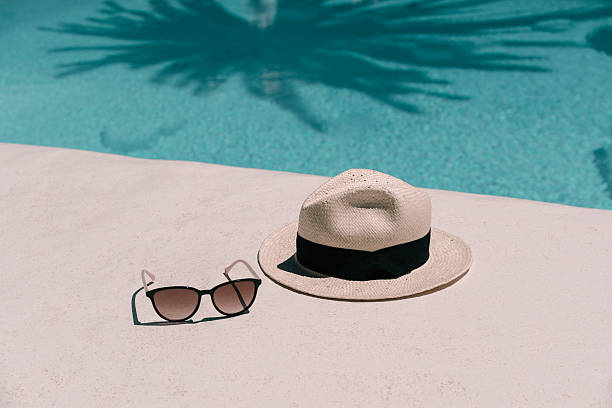 istock Straw hat, sunglasses at poolside. Summer vacation holidays. Swimming pool with a palm tree shadow 2213851389