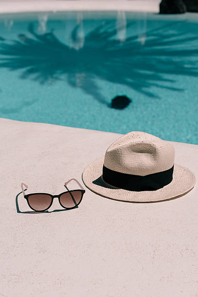 istock Straw hat, sunglasses at poolside. Summer vacation holidays. Swimming pool with a palm tree shadow 2213851393