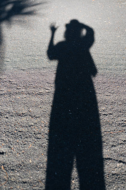 istock Shadow of a waving person in a hat on a white wall 2213851417
