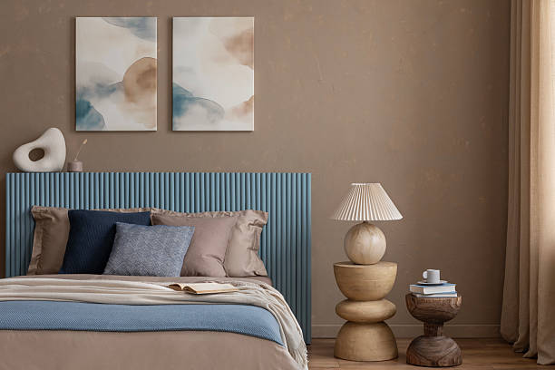 istock Cozy bedroom setting with a blue paneled headboard, neutral bedding, and abstract wall art in warm earth tones. 2213852049