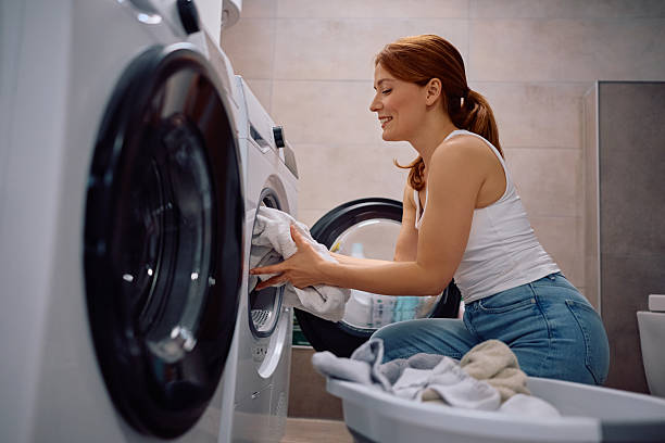 istock Happy woman loading the laundry in washing machine. 2213853814
