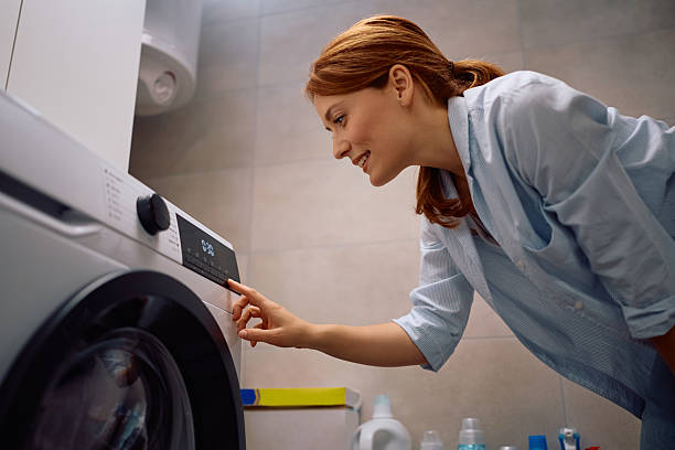 istock Smiling woman turning on washing machine while doing laundry at home. 2213853901