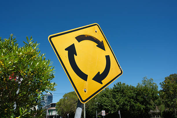 Yellow traffic sign with blue sky and trees behind.