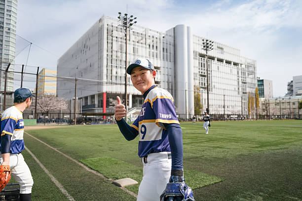 A player from a Tokyo-based community baseball team smiles confidently at the camera, showcasing the camaraderie and sportsmanship fostered among teammates during a sunny day on a city sports field.