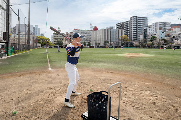 istock Baseball Player Practicing Batting at a Community Field in Urban Tokyo 2213856425