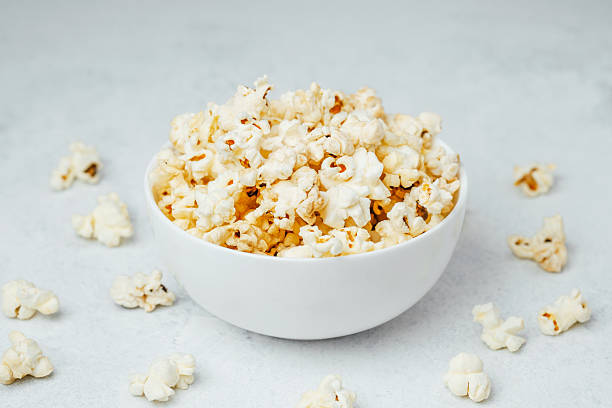 istock Fluffy popcorn in a white bowl surrounded by scattered kernels 2213856945
