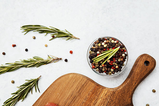 An assortment of colorful spices in a bowl alongside fresh herbs on a cutting board.