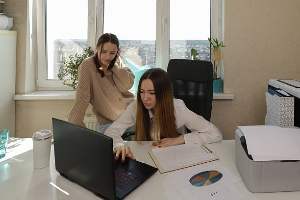 istock young women analyzing paperwork at an office workstation, set against a brightly lit backdrop, suitable for illustrating planning, strategy sessions, or innovative workplace scenarios. 2213859393